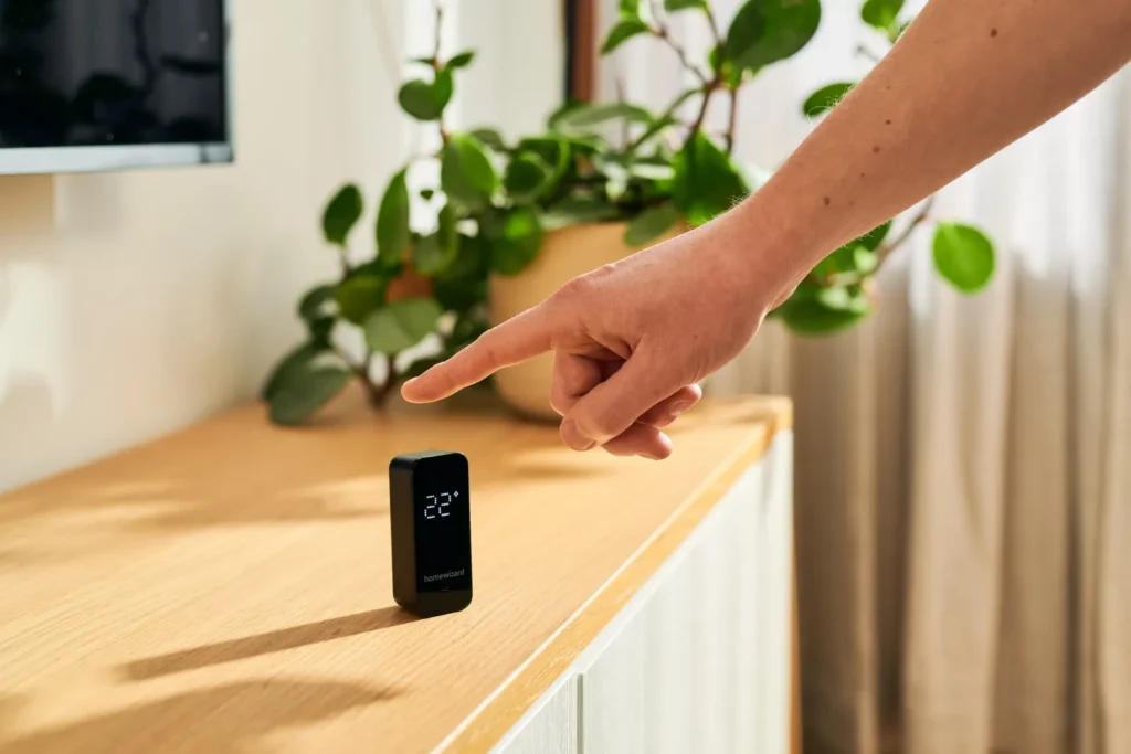 Hand tikt op de Temperature Humidity Meter op een dressoir om de temperatuur af te lezen
